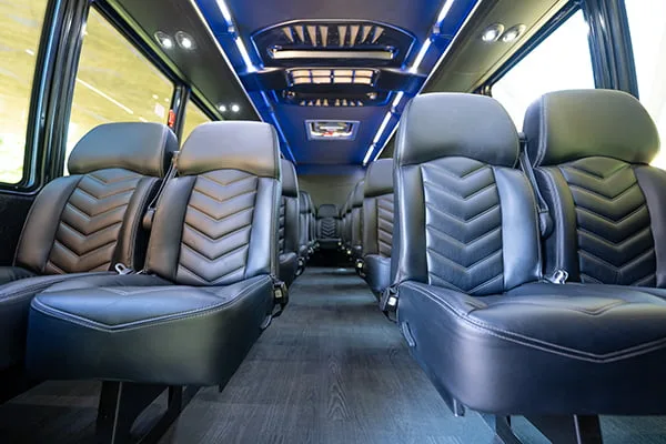 Executive shuttle bus interior with reclining leather seats and LED lighting