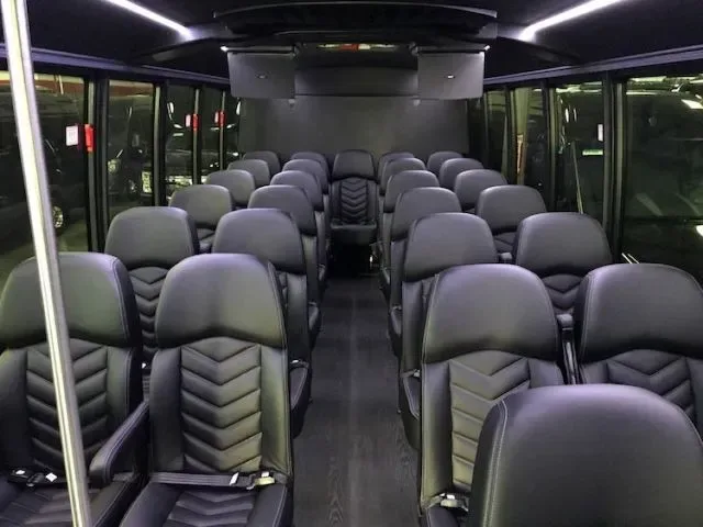 Shuttle bus interior with rows of black leather seats