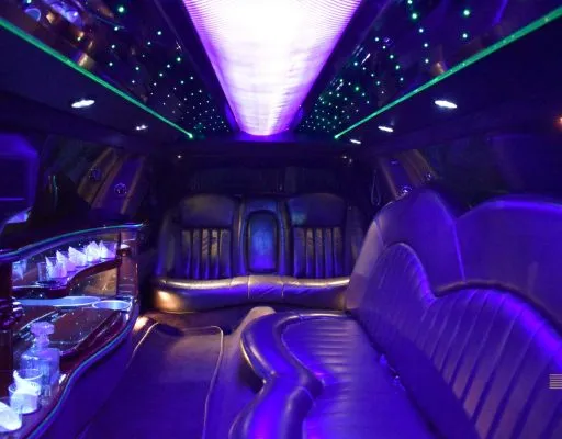 Stretch limo interior with purple mood lighting and bar area