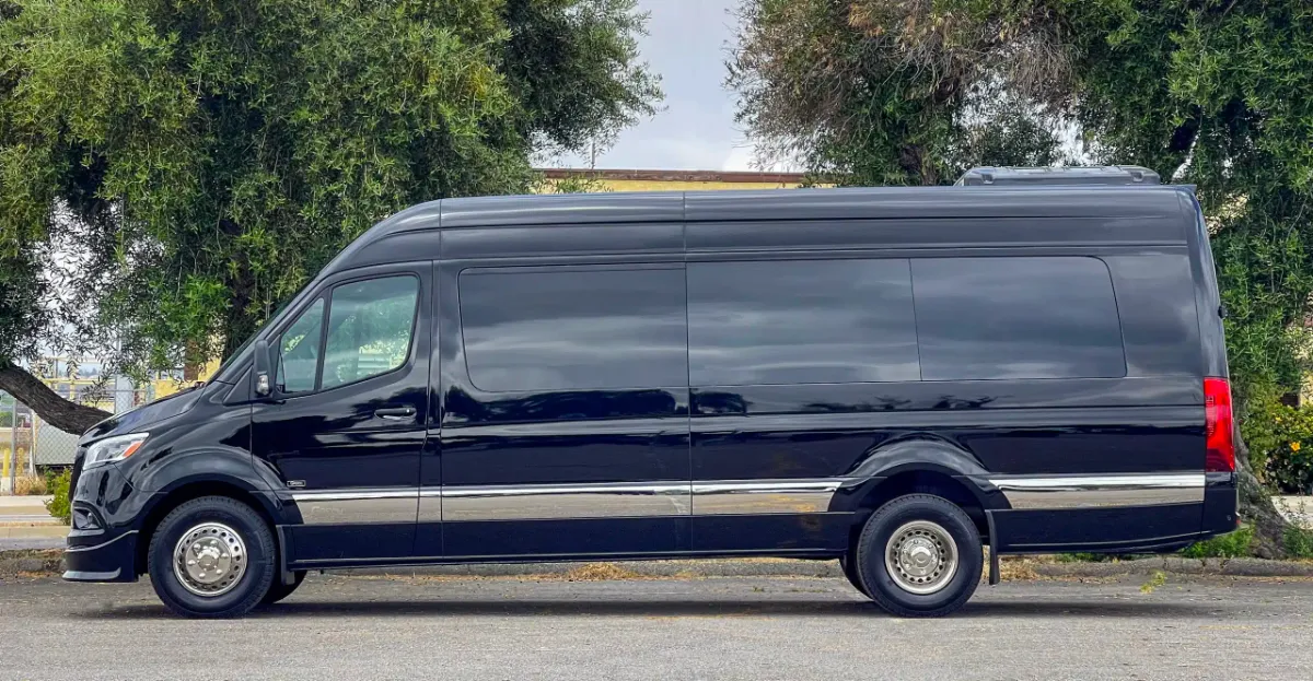 Black executive Mercedes Sprinter van parked on a tree-lined street