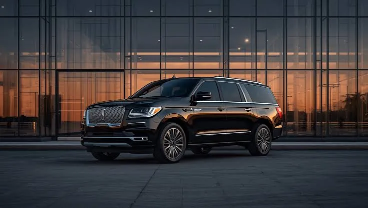 Black Lincoln Navigator executive SUV parked outside a glass office building at sunset
