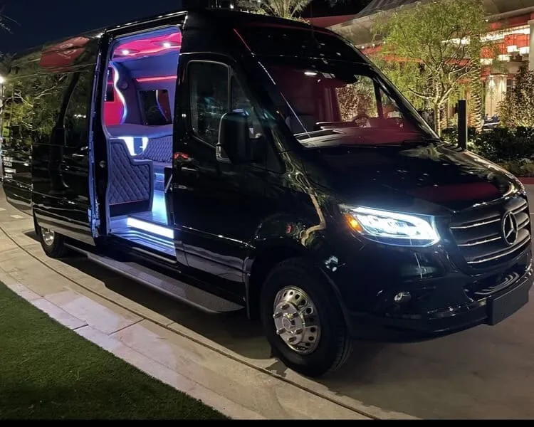 Black Mercedes limo Sprinter at night with its side door open and interior lights on