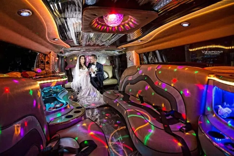 Bride and groom inside a Hummer limo with colorful party lights and lounge seating