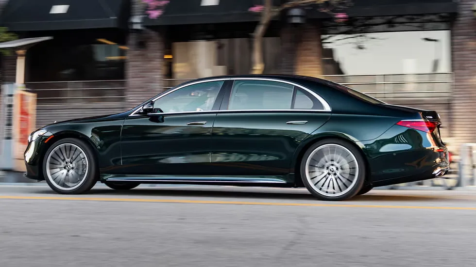 Long black Mercedes luxury sedan side profile on a city street
