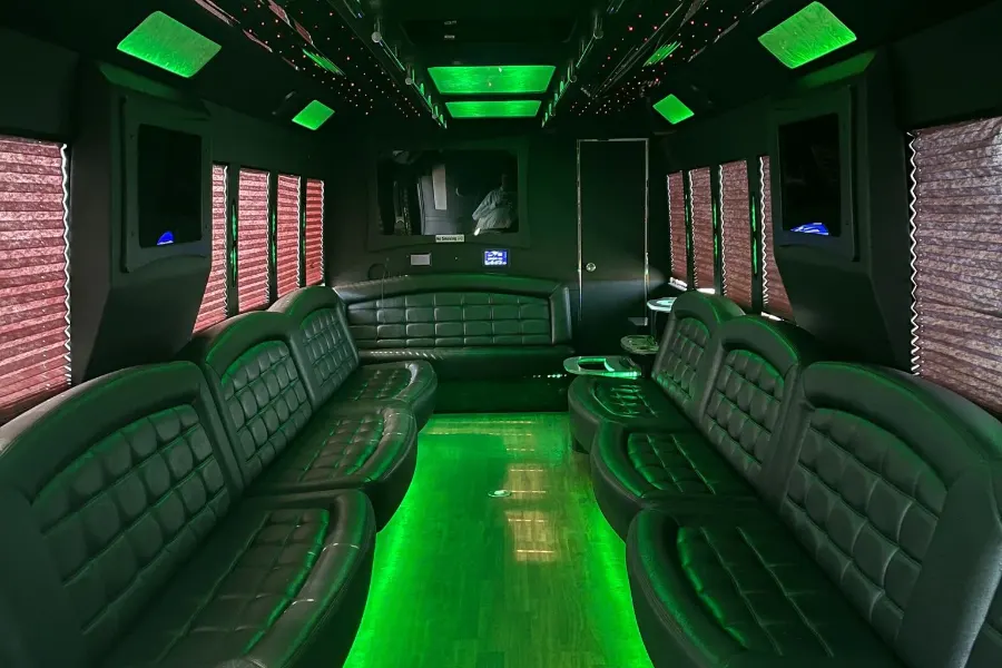 Party bus interior with green LED floor lighting and lounge seating along both sides