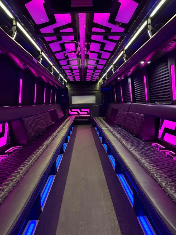 Long party bus interior with purple ceiling lights and blue floor lighting