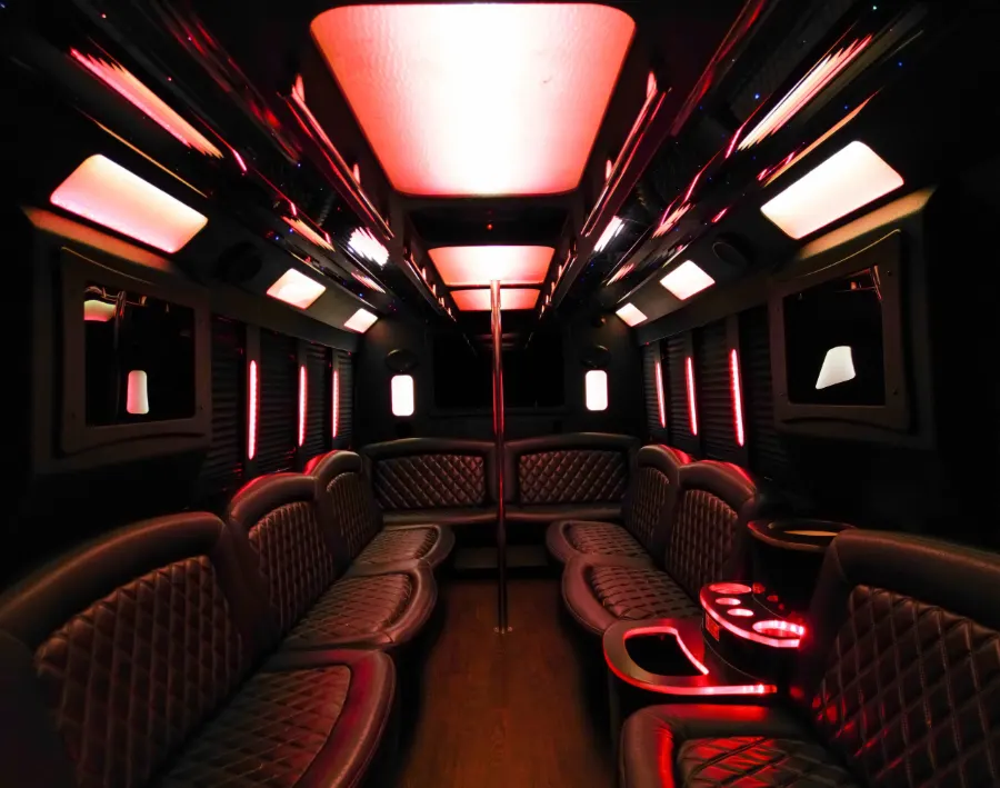 Party bus lounge seating with cup holders under a glowing LED ceiling