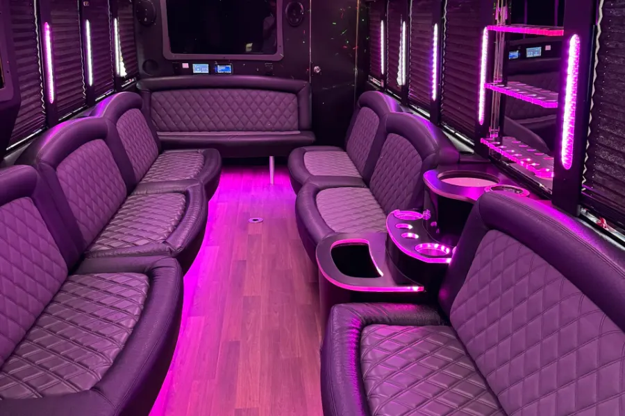 Party bus interior with purple lighting and quilted lounge seating