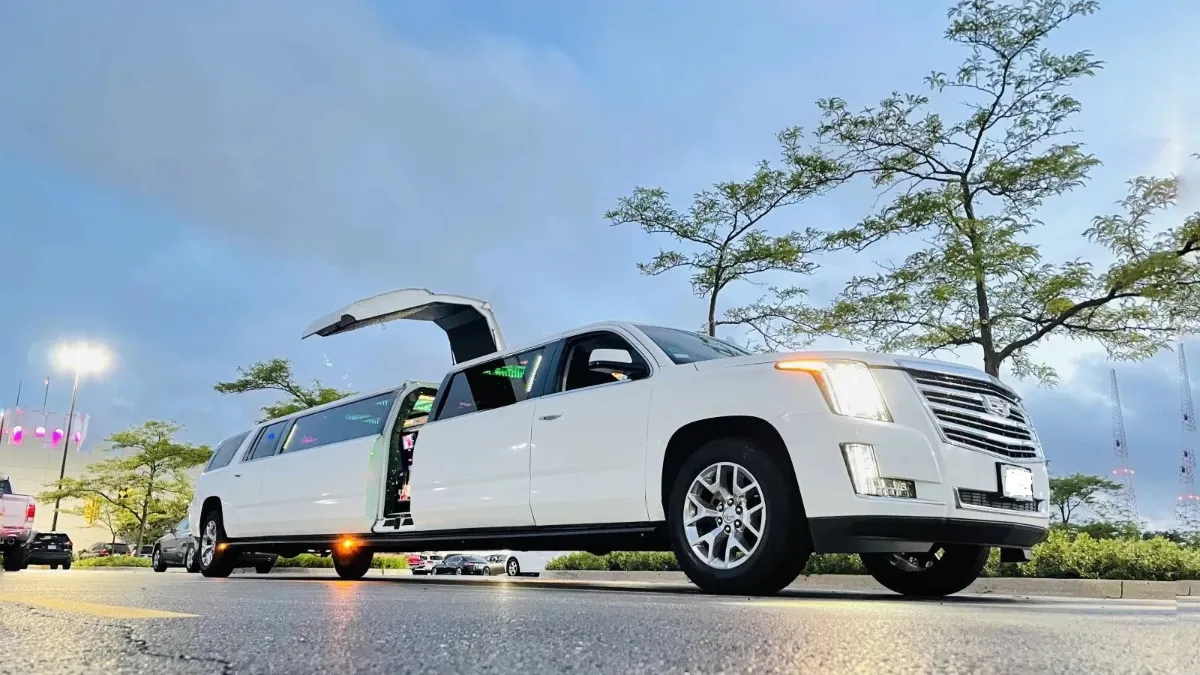 White Cadillac Escalade stretch limo with its doors open at dusk
