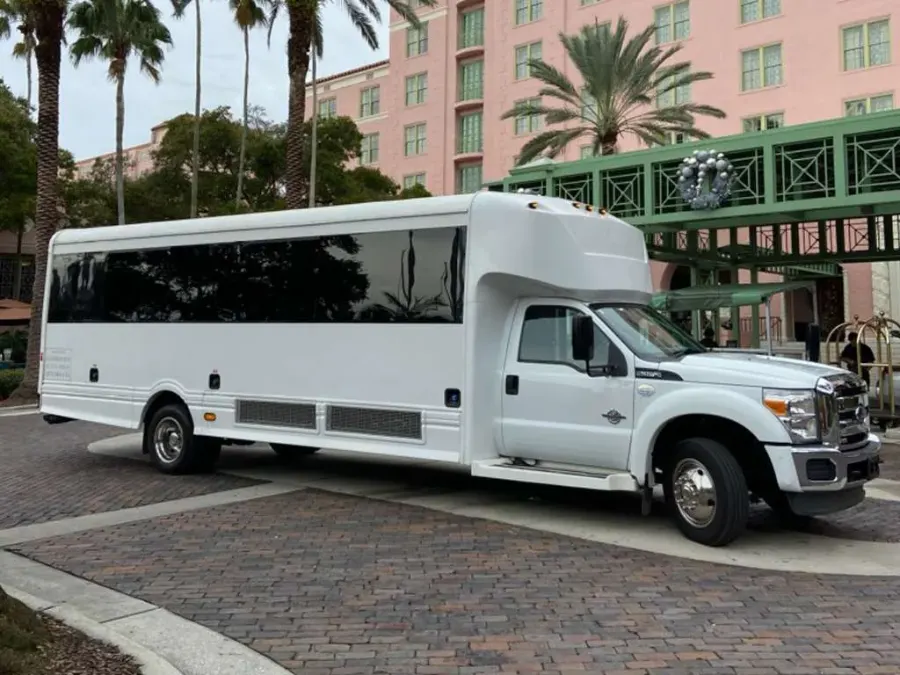 White party bus waiting at a hotel entrance for a group pickup